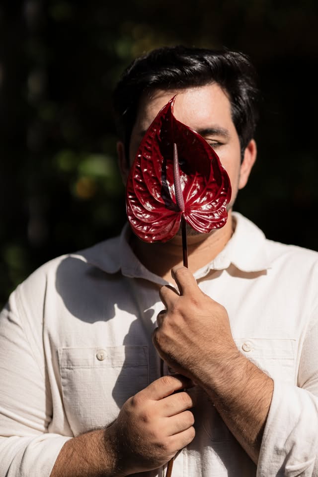 Carlos da CAZ Estúdio Floral segurando um antúrio vinho